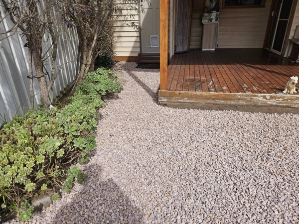 A pebbled yard with stepping stones running to a timber deck