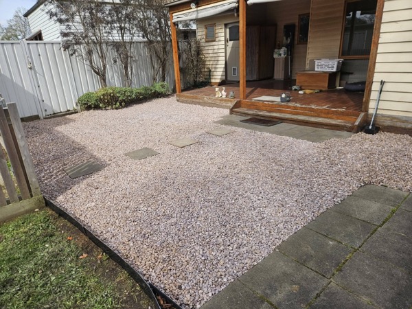 A pebbled yard leading up to a verandah with a timber deck