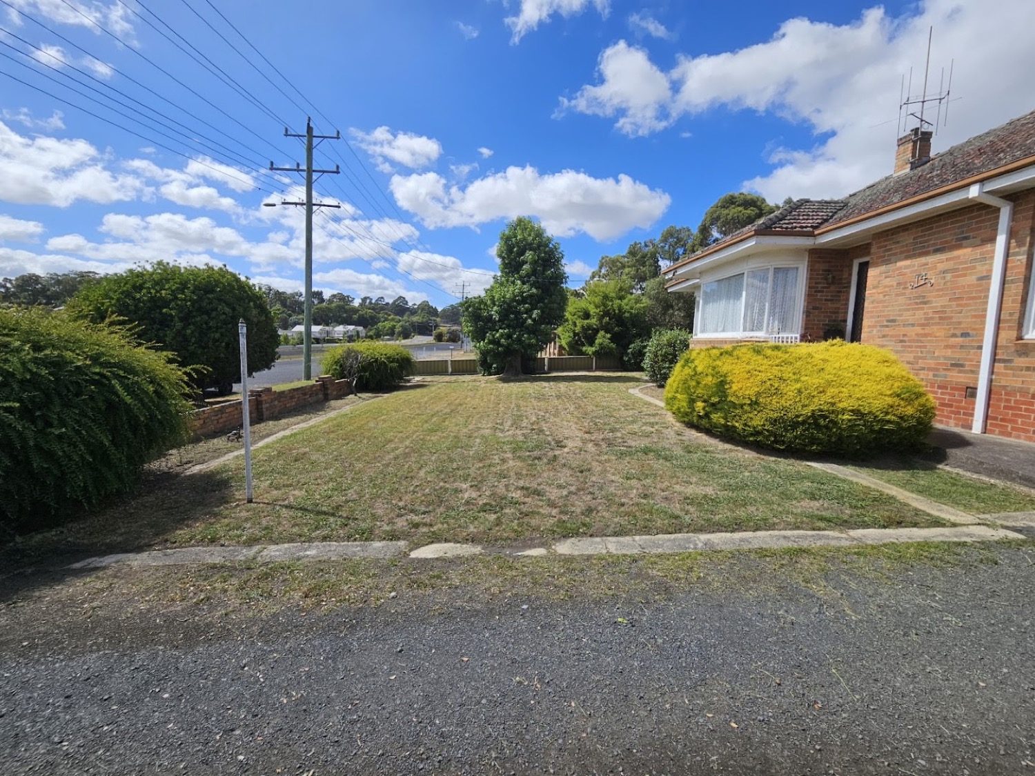 A mown front lawn and driveway in front of a brick house