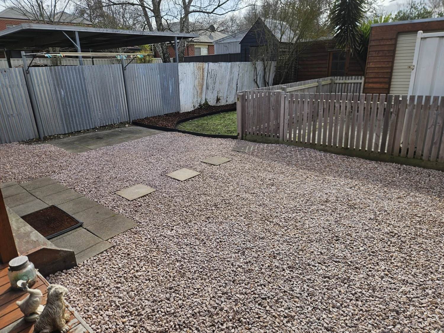 A back yard finished in pebble with concrete pavers set into it
